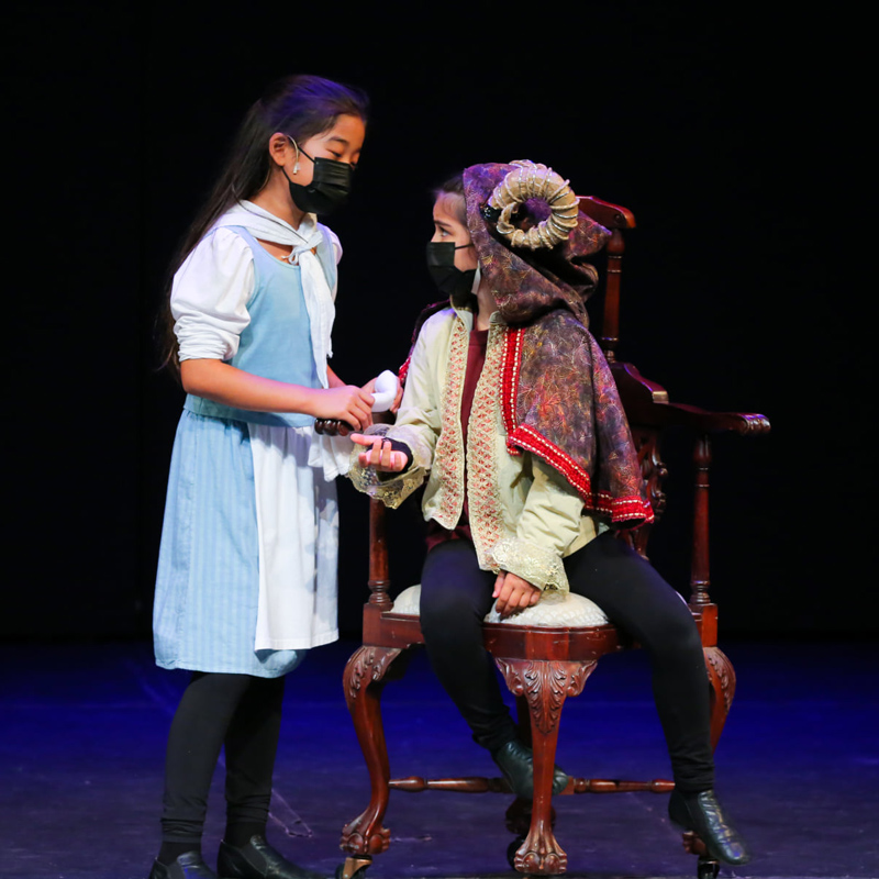 Two children on stage acting in Beauty and the Beast